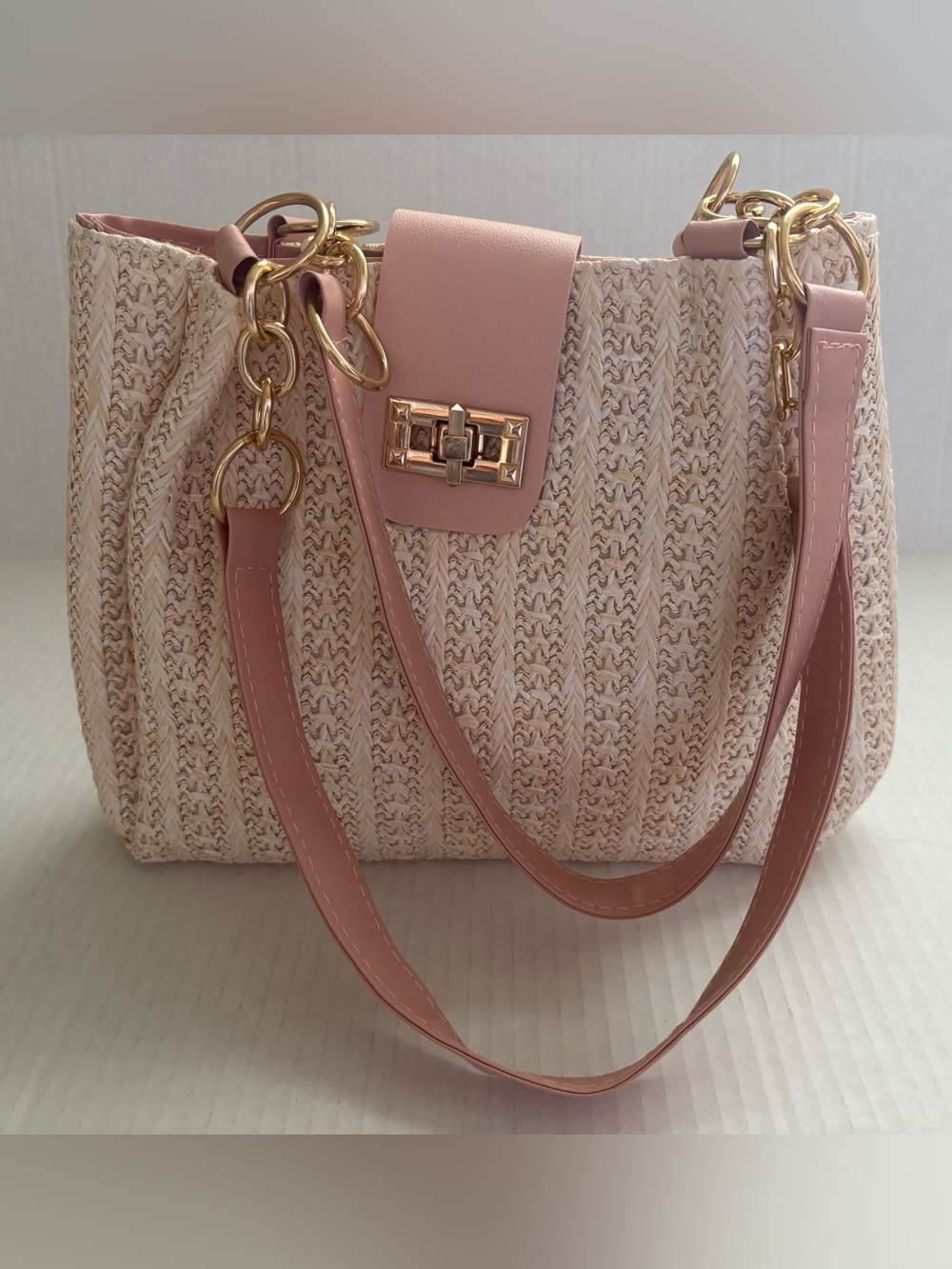 Woven Cream handbag features a pink faux leather flap closure gold lock.